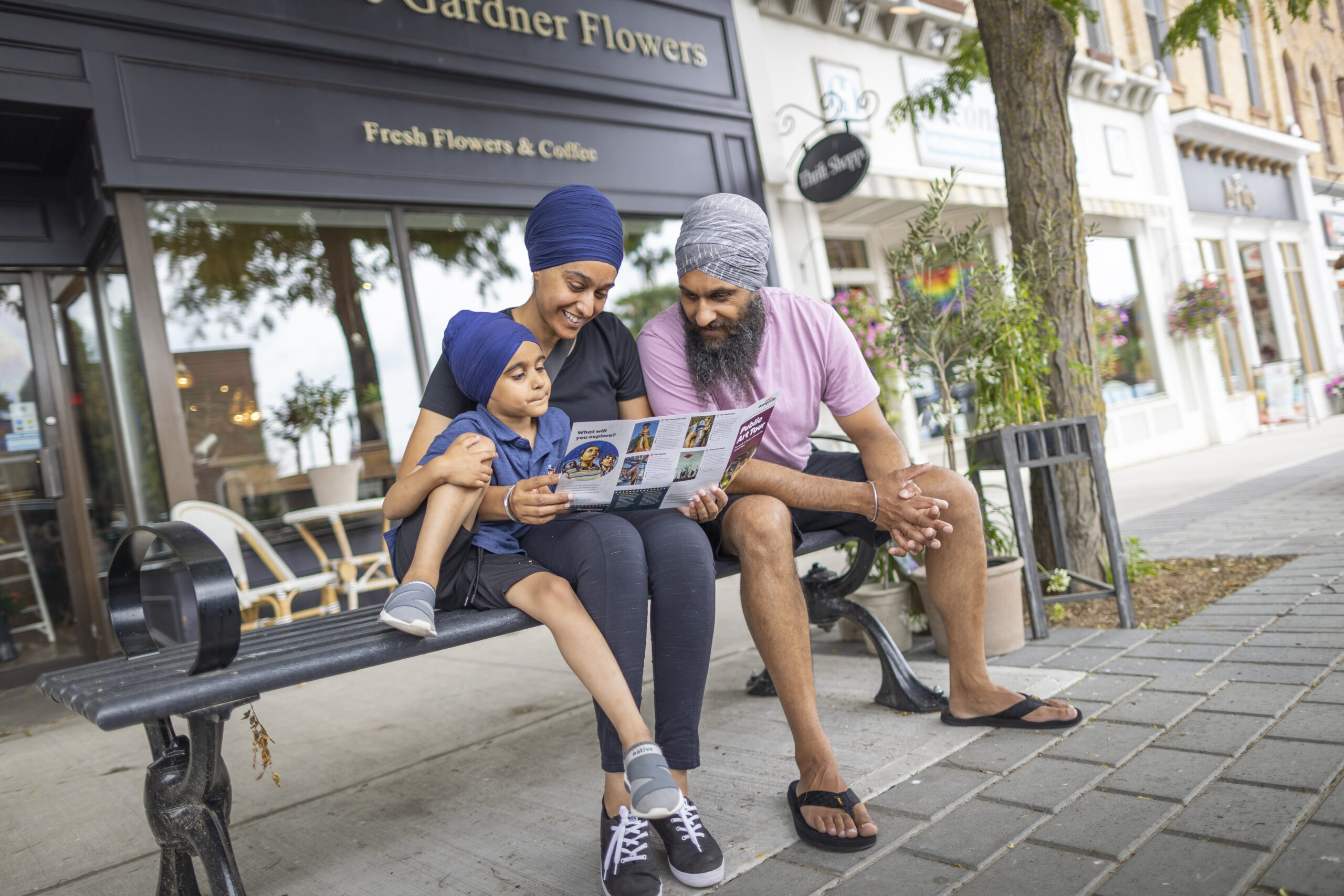 A young Sikh family reading through a guide on a bench in downtown orangeville