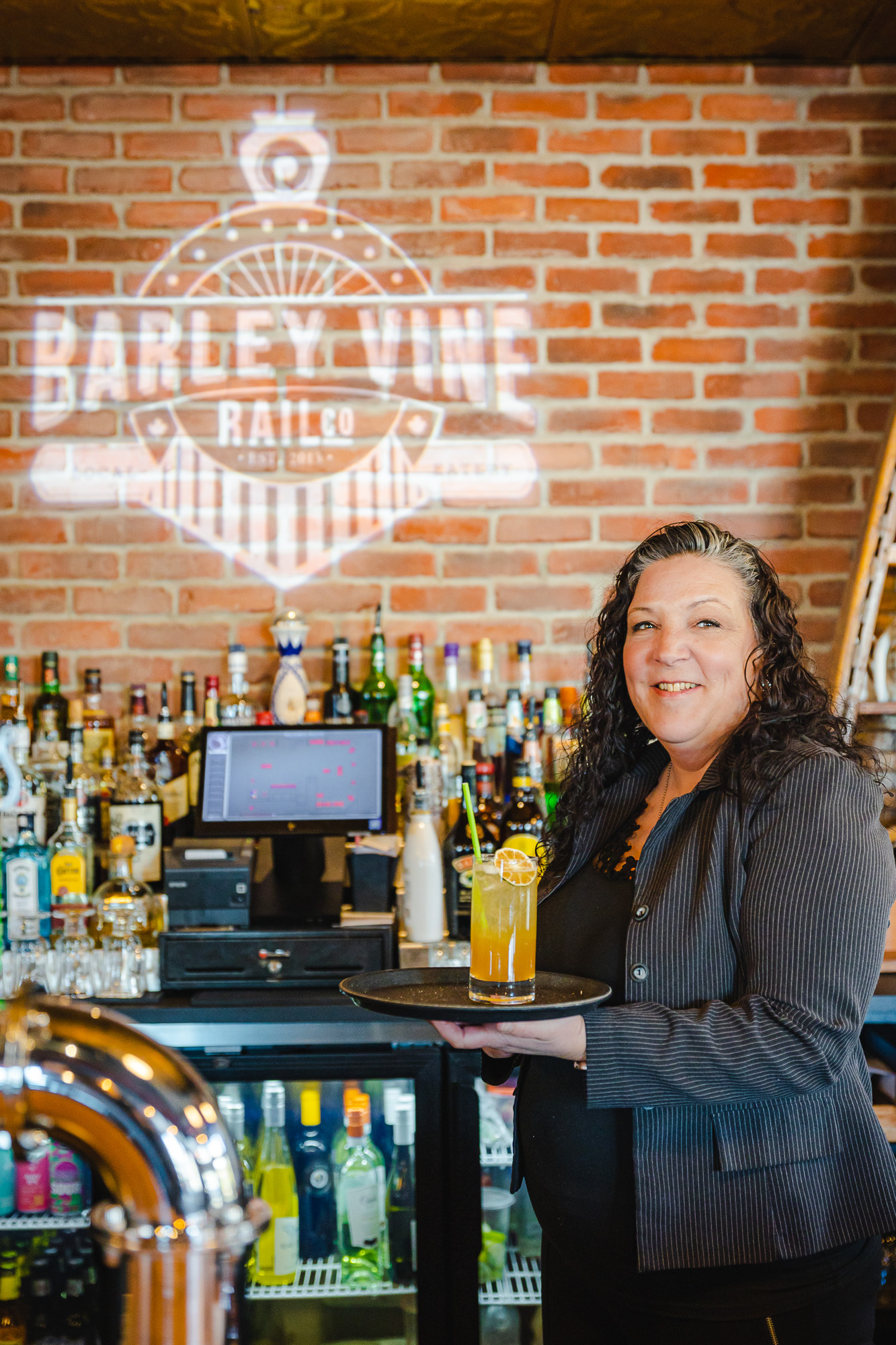 lady standing by the bar and holding a drink at the Barley Vince Rail Co.