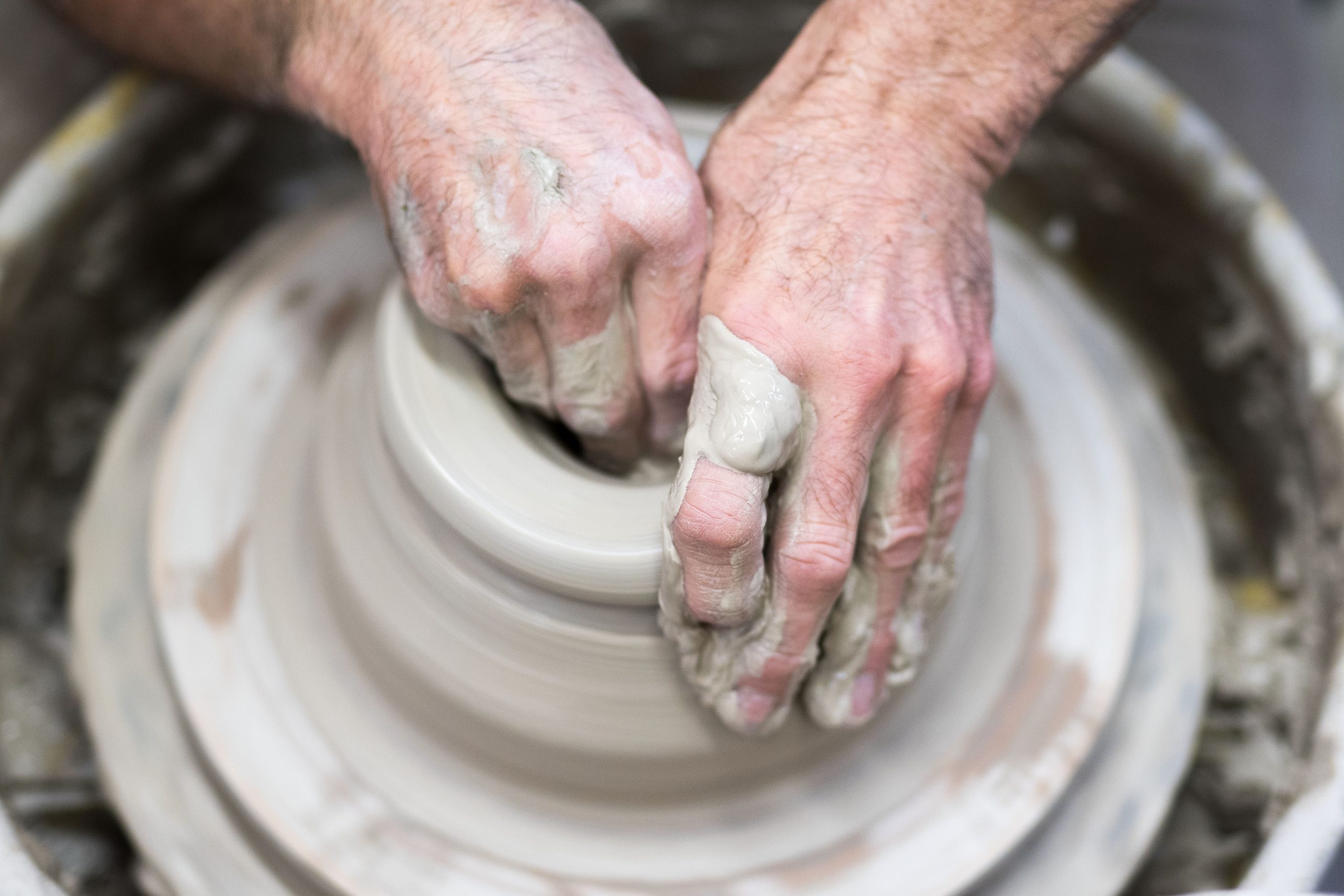 hands working on a new piece of pottery