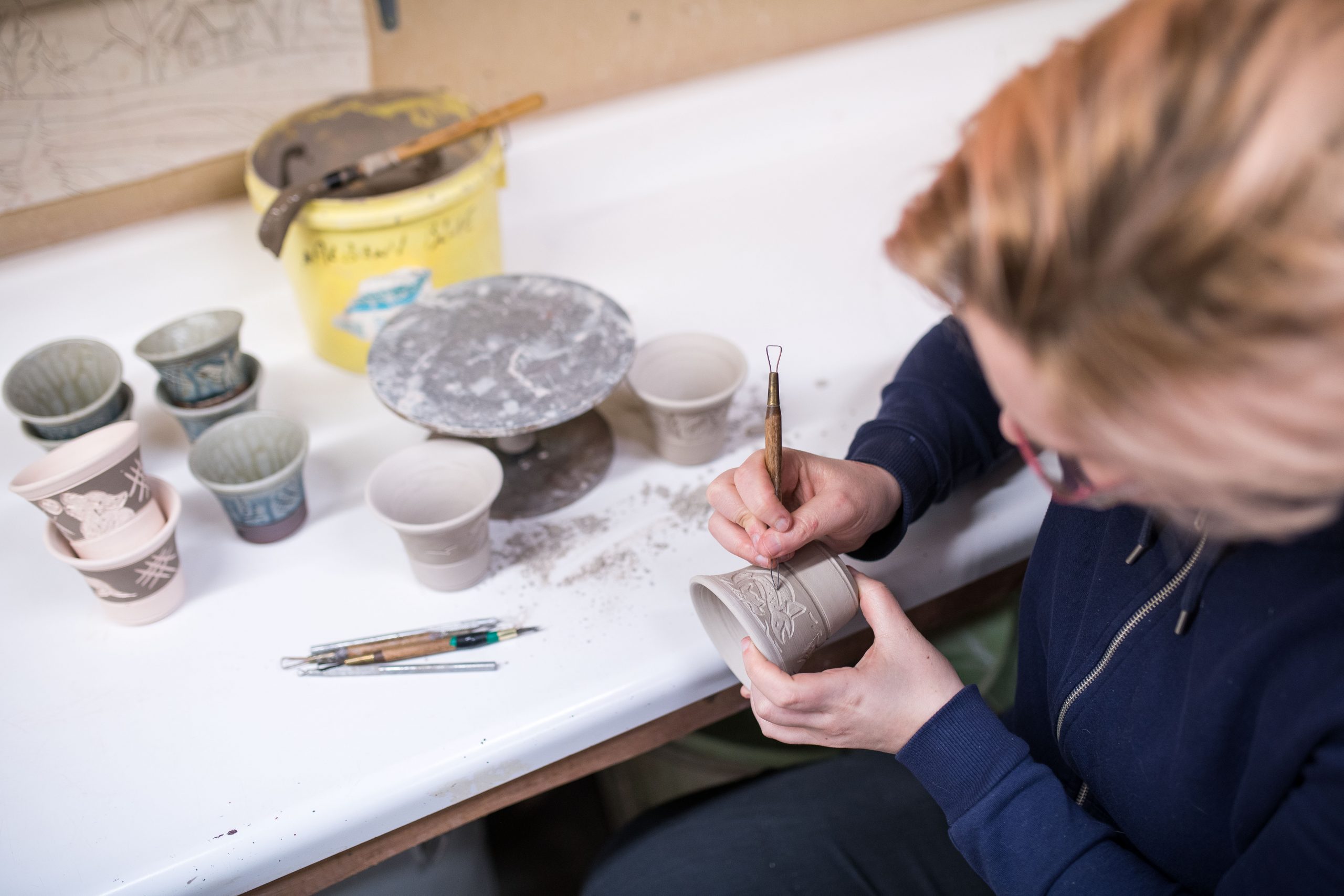 A woman etches markings into pottery.