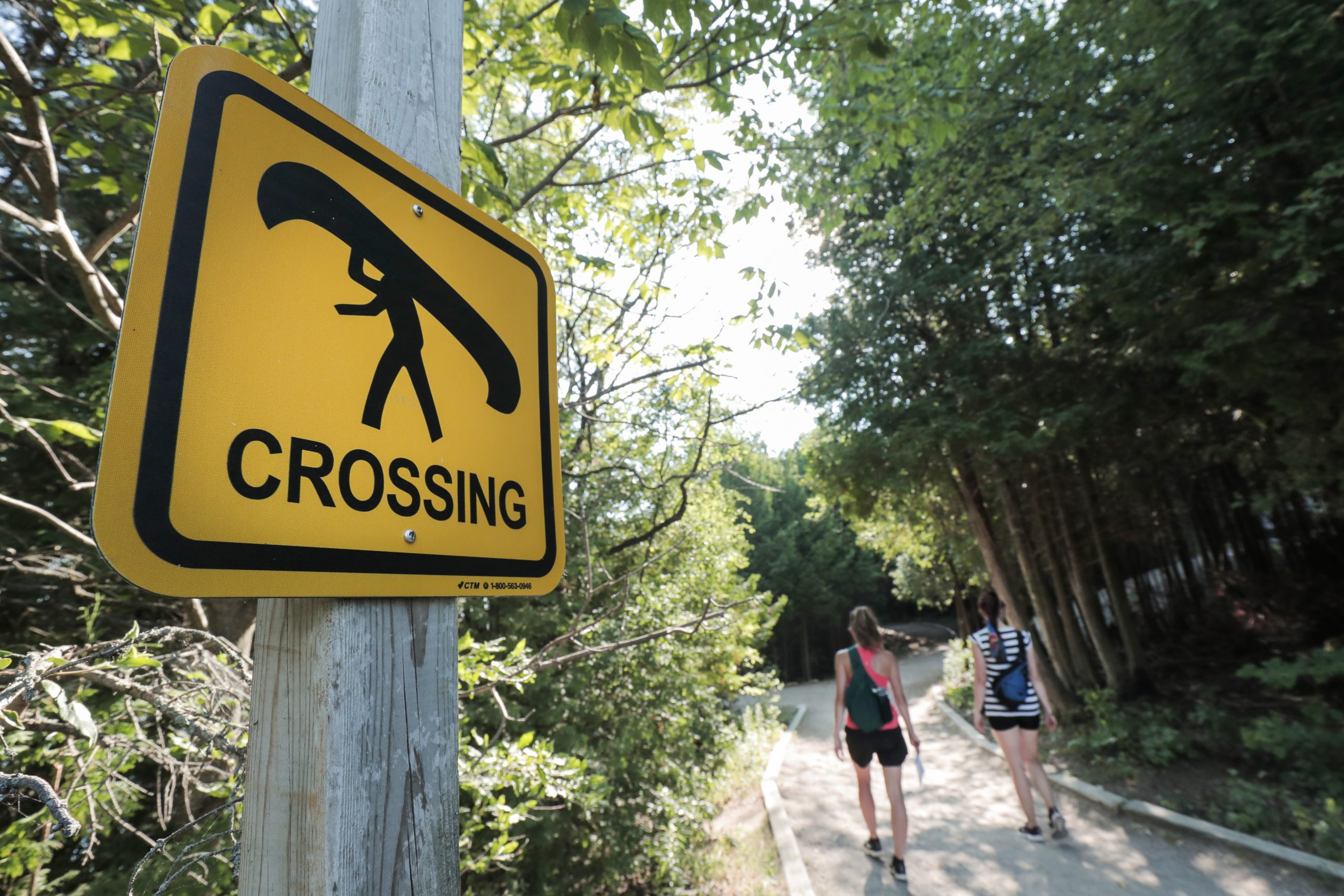 Canoe crossing sign at island lake with people walking in the distance