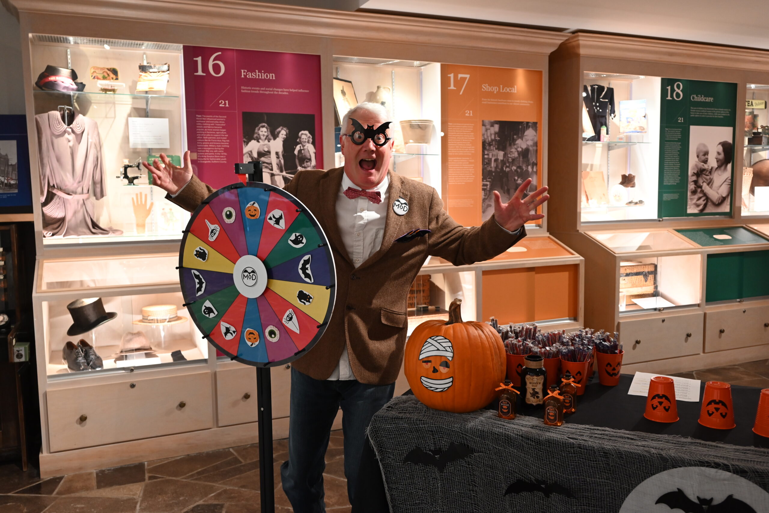 A man dressed up in a Halloween costume with a spin wheel at the museum