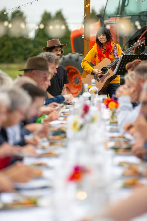 people enjoyng a mean on the table in the outdoors at lennox farm with live music.